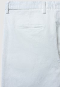 Pantaloni di velluto bianco con texture a coste, taglio dritto e una tasca posteriore singola con dettagli di cucitura sottili.