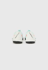 Chaussures de football blanches et vert menthe avec des crampons en caoutchouc noir, portant le texte "PHANTOM" en noir et un accent corail sur les côtés.
