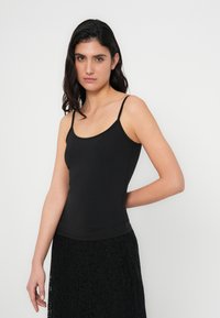 Sort tanktop med tynde stropper, lavet af glat stof. Har en tætsiddende silhuet og et enkelt design uden mønstre eller pynt.