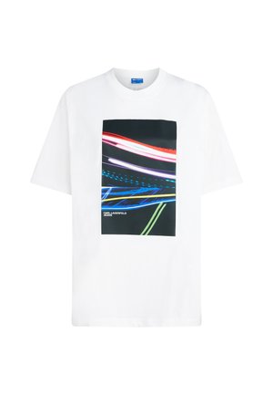 Balta medvilnės marškinėliai su geometriniu grafiniu spaudiniu, kuriame raudonos, mėlynos ir žalios šviesos pėdsakai tamsiame fone. Įtraukta Karl Lagerfeld Jeans logotipas.