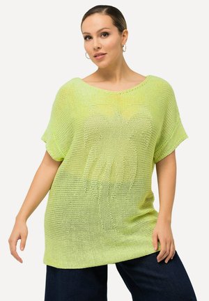 T-shirt tricoté surdimensionné vert lime avec des manches courtes, arborant un motif texturé. Le tissu semble léger et respirant.