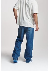 Slöa blå denimjeans med en blekt tvättad yta, ihop med en löst sittande vit t-shirt. Avslappnad stil och bekväm passform är tydliga.