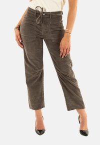 Pantaloni in velluto a coste marroni con un fit rilassato, vita alta, cordoncino e tasche frontali, caratterizzati da linee verticali testurizzate e taglio alla caviglia.