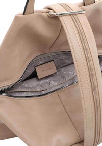 Borsa a mano in pelle beige con scomparto con zip. L'interno presenta una fodera con motivo e un'etichetta di marca. Texture liscia e forma morbida.