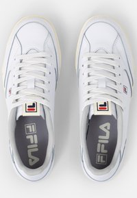 Weiße Sportschuhe mit grauen Akzenten, Schnürdesign, glattes Lederobermaterial, gepolsterte Innensohlen und Markenlogo an der Ferse und Zunge.