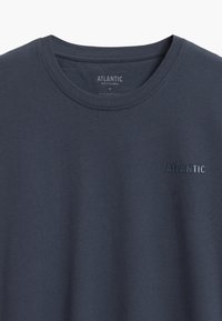 Szara bawełniana koszulka z okrągłym dekoltem i subtelnym logo "ATLANTIC" w ciemniejszym odcieniu szarości. Gładka tekstura i prosty design.