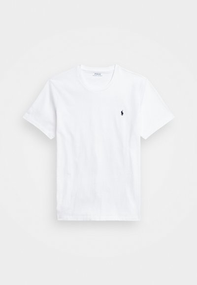Valkoinen puuvillainen T-paita, jossa on pyöreä pääntie ja lyhyet hihat. Vasemmassa rintakehässä on pieni tumma logo. Pehmeä rakenne.