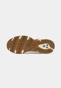 Sport sneaker featuring a patterned rubber outsole with brown accents and blue details, designed for traction and durability.