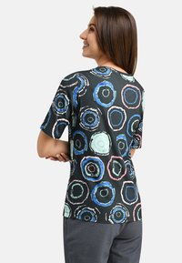 Short-sleeve black t-shirt with multicolored circular patterns. Made of soft fabric, featuring a relaxed fit and round neckline.