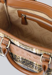 Texturerad handväska med bruna läderhandtag och detaljer, som har ett internt ficka med dragkedja och ett mönstrat tygfoder i neutrala nyanser.