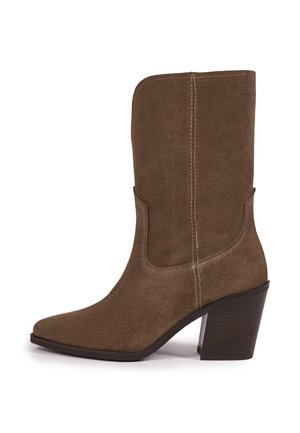 Brauner Wildleder-Stiefel bis zur Mitte der Wade mit spitzer Spitze, sichtbaren Nähten und klobigem, gestapeltem hohen Absatz auf weißem Hintergrund.
