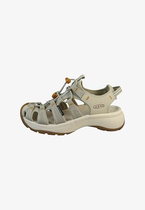 Lys beige vandtætte sandaler med en overdel i mesh og syntetisk materiale, justerbare bungee-snører og en polstret sål med godt greb.