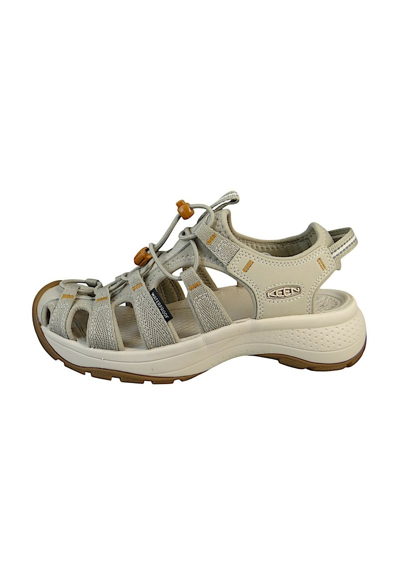 Light beige waterproof sandals featuring a mesh and synthetic upper, adjustable bungee laces, and a cushioned sole with grip.