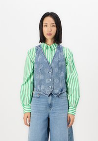 Denim vest with a light wash, featuring five buttons, a V-neckline, and floral pattern accents, layered over a green and white striped shirt.