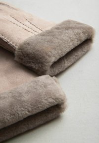 Beige ruskindhansker med bløde, fyldige pelsmanchetter. Manchetterne er tykkere og strukturérte, mens håndfladerne viser subtile syningsdetaljer.