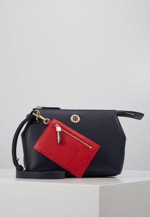 Petit sac bandoulière en cuir noir avec logo et éléments en métal doré, doté d'un porte-cartes rouge amovible avec poche zippée à l'avant.