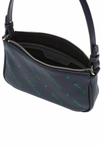 Granatowa skórzana torebka o gładkiej fakturze, z zielonym nadrukowanym logo i zapięciem na zamek. Krótki regulowany pasek dla wygody.