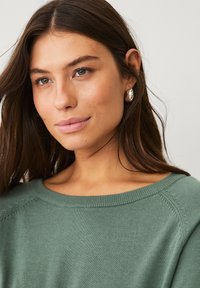 Maglione verde in maglia con scollatura ampia e polsini a costine. Tessuto morbido e vestibilità comoda, che mette in risalto un design semplice e pulito.