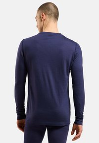 Chemise à manches longues bleu marine en tissu doux, avec un col rond et un design ajusté aux manches longues.