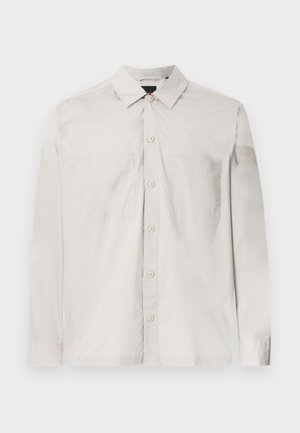 Lichtbeige overhemd met lange mouwen, knoopsluiting, twee borstzakken en een klein logoplaatje op de linkermouw.