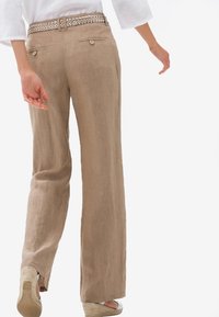 Beige linnebyxor med vida ben och strukturerad yta, med ett flätat bälte och två bakfickor, matchade med vita espadriller.