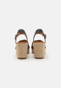 Sorte skinn wedgesandaler med espadrille tau-helt, med justerbar ankelrem og en tan fotseng. Firkantet hældesign.