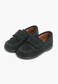 Scarpe in suede nero con cinturino in velcro, dotate di cuciture lungo i bordi e di una morbida fodera in pelle. Suola piatta in gomma.