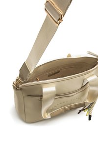 Sac cabas beige avec une finition brillante, fermeture éclair, deux poignées en tissu, et une bandoulière tissée amovible. L'intérieur comprend une poche zippée.