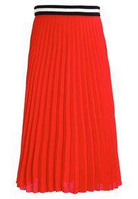 Jupe plissée rouge avec une large ceinture à rayures noires et blanches. Tissu léger avec une texture lisse, tombant à mi-mollet.