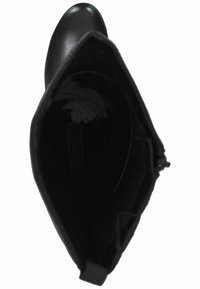 Botte noire en cuir montant jusqu'au genou vue de dessus, montrant l'orteil pointu, la doublure intérieure et un tissu blanc plié à l'intérieur.