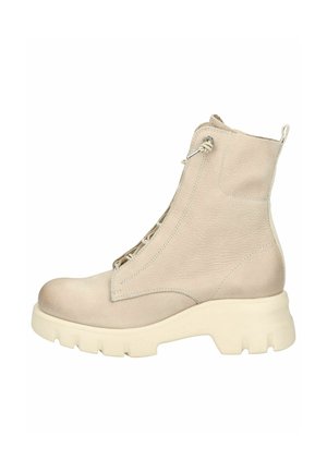 Bottine beige en cuir texturé, dotée d'une semelle blanche épaisse, de lacets sur le devant et d'une languette à l'arrière.