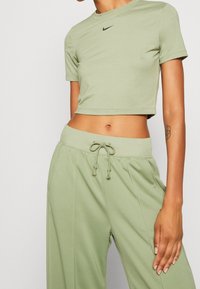 Světl zelené sportovní tričko s krátkým rukávem a černým logem Nike. Koordinující světl zelené volné kalhoty s drawstring pasem.
