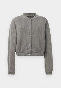 Veste grise courte avec un motif texturé, dotée d'un col rond, de manches longues et de fermetures à boutons-pression sur le devant.