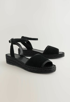 Sandale espadrile din suede negru, cu vârfuri deschise, curea pentru gleznă și talpă din iută împletită neagră. Au o branț din piele netedă.