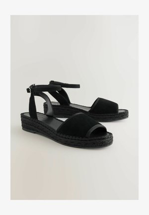 Black suede espadrille sandals with open toes, ankle strap, and braided black jute sole. Features a smooth leather insole.