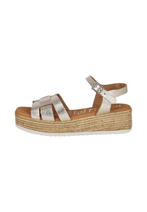 Sandalia de cuña con tiras metálicas plateadas, hebilla ajustable en el tobillo y plataforma trenzada de yute con suela blanca estriada.