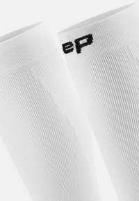 Weiße knielange Socken mit einem gerippten Textur. Oben befindet sich ein schwarzes Logo "ep" zur Markenkennzeichnung. Leichtes, dehnbares Material für Komfort.