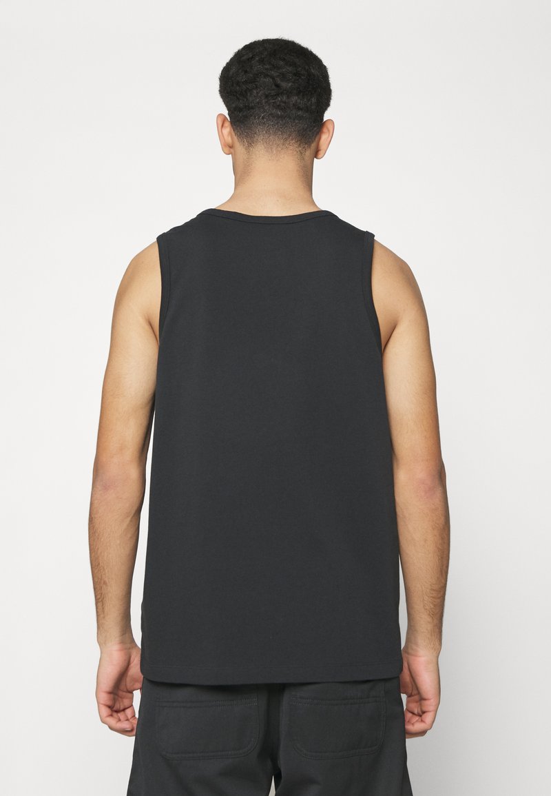 Top sin mangas de algodón negro con cuello redondo, de color sólido y corte relajado. Presenta una textura suave y un diseño casual.