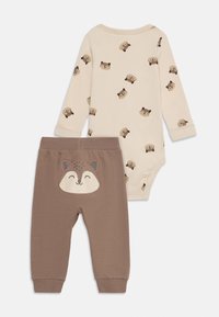 To-delt baby outfit bestående af en lys beige body med et mønster af brune dyrehoveder, parret med brune bukser, der viser et smilende dyr på bagdelen.
