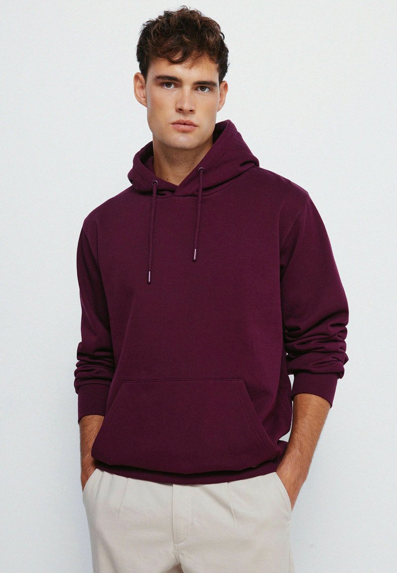 Hoodie color bordeaux con tasca frontale, cappuccio regolabile con lacci, polsini a costine e una texture liscia. Vestibilità casual, tessuto in misto cotone.