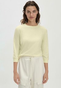 Hellgelbes, langärmliges Oberteil mit Rundhalsausschnitt und gerippten Bündchen, kombiniert mit weißen Hose mit Kordelzug an der Taille. Weicher Stoff mit lässiger Passform.