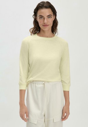 Hellgelbes, langärmliges Oberteil mit Rundhalsausschnitt und gerippten Bündchen, kombiniert mit weißen Hose mit Kordelzug an der Taille. Weicher Stoff mit lässiger Passform.