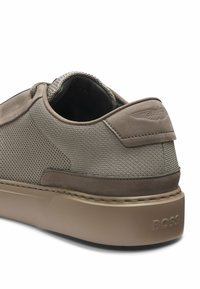 Baskets basses beiges en tissu texturé avec des panneaux en daim, semelle amortie et "BOSS" embossé sur le contrefort du talon.