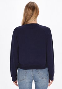 Pulover tricotat de culoare bleumarin, cu guler rotund, manșete și tiv cu nervuri. Prezintă mâneci raglan și o textură fină.