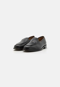 Black leather loafers with a smooth finish, almond-shaped toe, and stitched detailing on the upper. Flat heel with a sleek design.