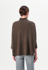 Pull en tricot marron avec un col haut et des manches trois-quarts. La coupe est ample avec une texture douce et un ourlet droit.