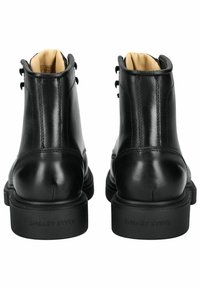 Stivaletti neri in pelle con una superficie liscia, punta rotonda e suola in gomma robusta. Presentano un design con lacci e dettagli cuciti.