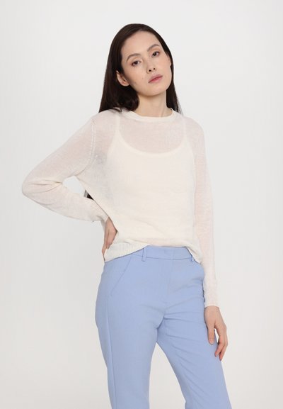Lightweight, sheer cream sweater with long sleeves, rounded neckline, and textured finish, paired with light blue tailored pants.