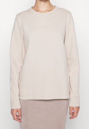 Felpa beige con maniche lunghe e scollatura rotonda. Presenta un tessuto morbido e un logo ricamato sul petto.