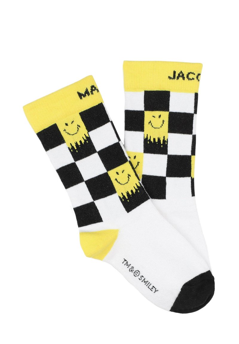 Chaussettes à carreaux noir et blanc avec des accents jaunes et un motif de smiley. Poignets côtes ; sections noire pour les orteils et le talon. Matériau en mélange de coton.